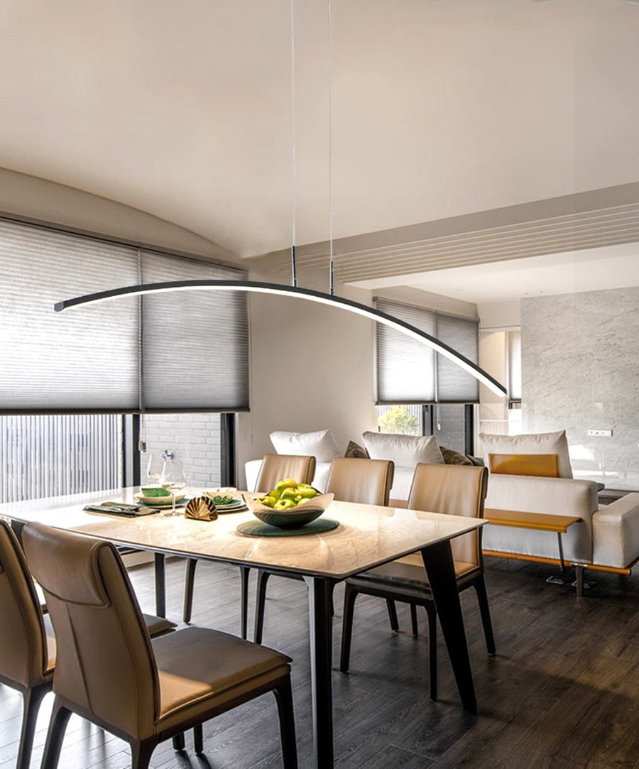 Modern LED pendant light with a curved design, installed over a dining table.
