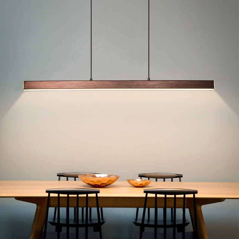 A modern LED chandelier in a contemporary dining room setting, with a long rectangular body suspended above a wooden table, featuring a dimmable light source with a remote control.