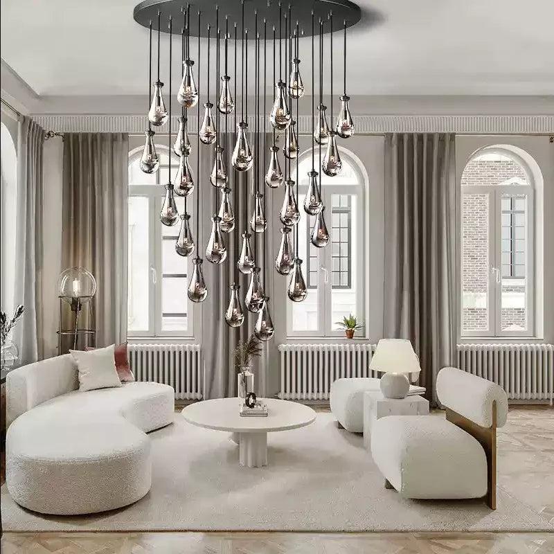 Raine Modern Chandelier with K9 crystal prisms and sleek metal design, perfect for high-ceiling living rooms, foyers, and upscale interiors. Adjustable height, energy-efficient LED compatible.