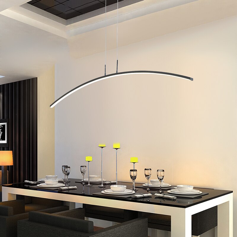 Modern LED pendant light with a curved design, installed over a dining table in a bright interior setting bringing a cozy feeling.