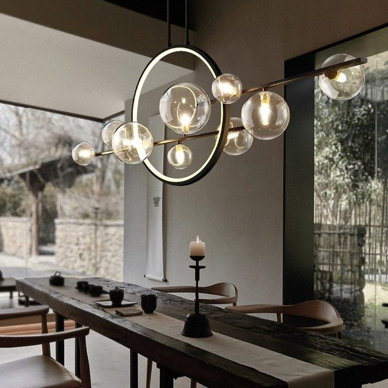 Modern hanging glass ball LED lighting fixture with a black finish, displayed over a dining table in a well-lit room.